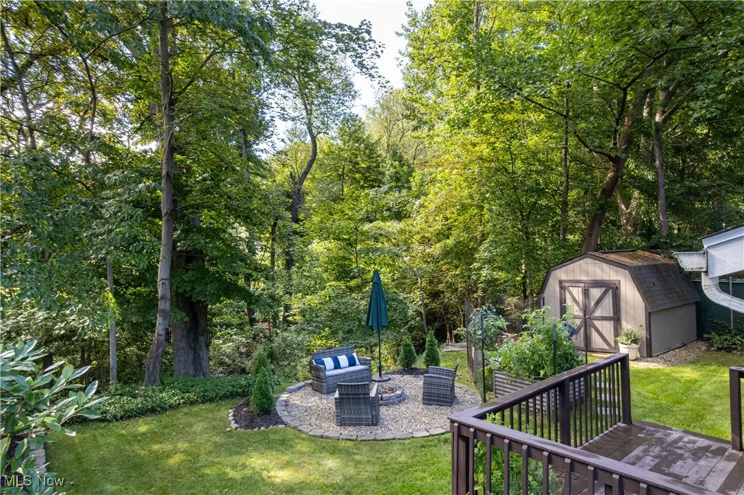 View of green lawn featuring a patio area, a storage unit, and a fire pit