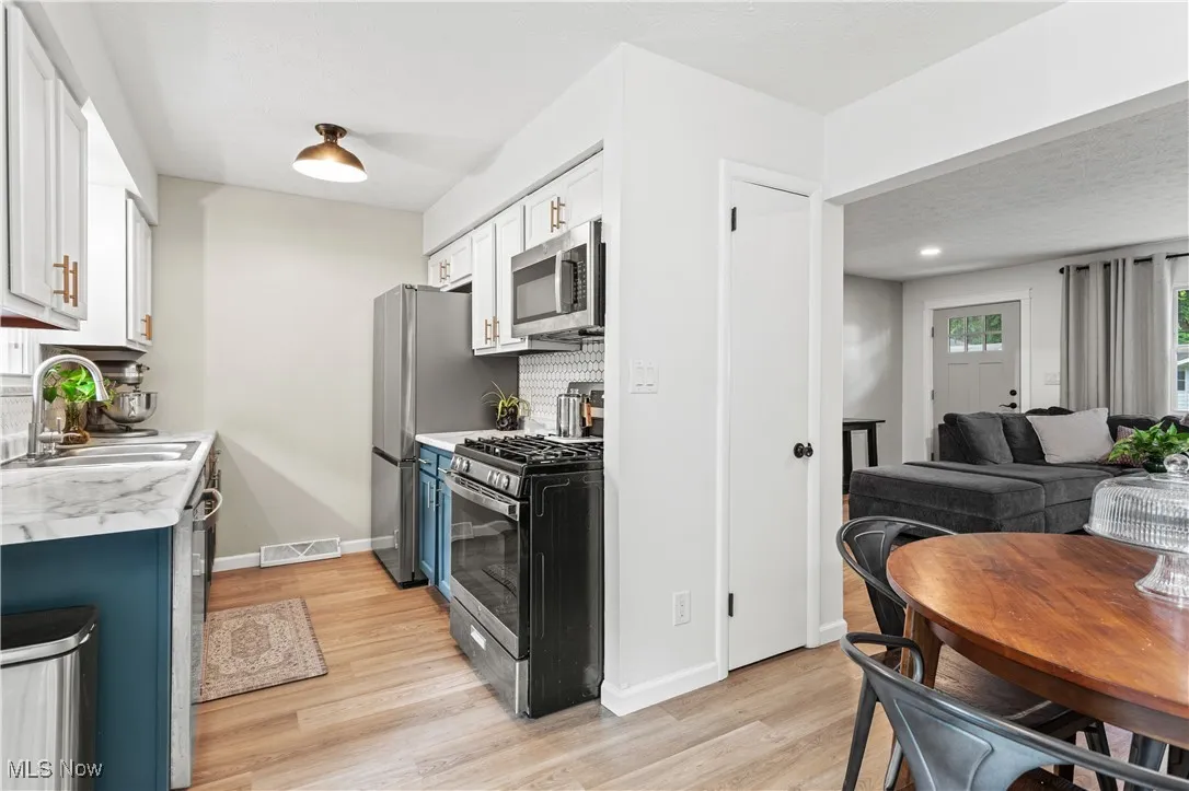 Kitchen with stainless steel appliances, white cabinetry, tasteful backsplash, light wood-style flooring, and open floor plan