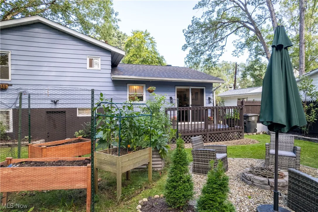 Back of property featuring a deck, a garden, and a shingled roof