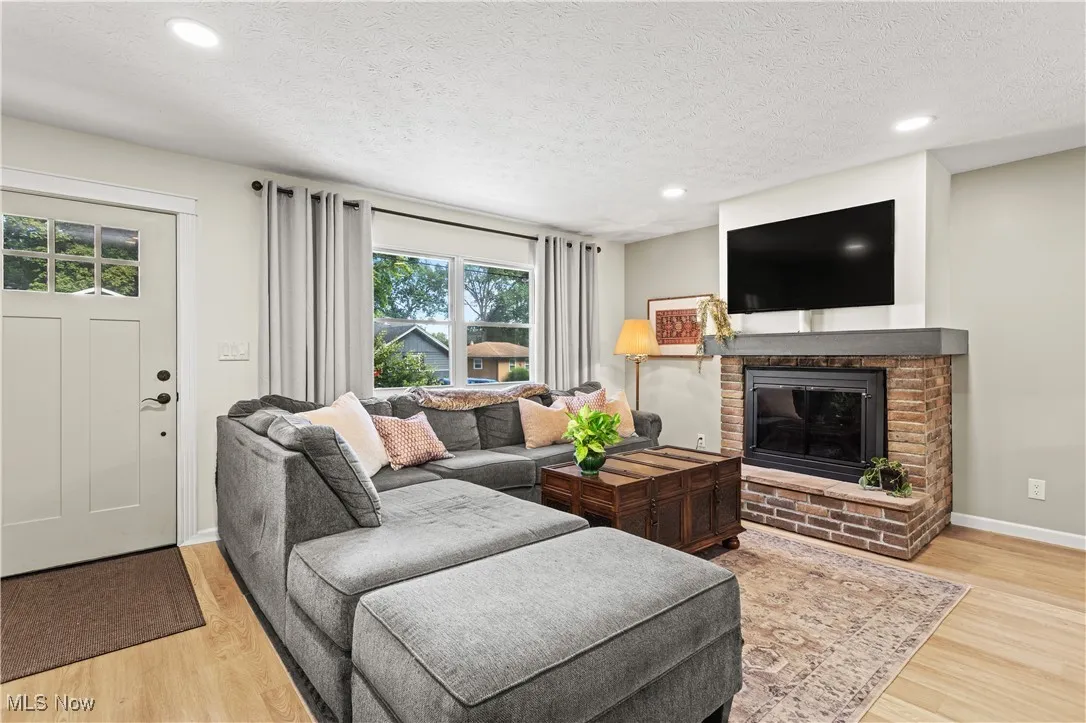 Living area with light wood-style floors, a fireplace, recessed lighting, and a textured ceiling
