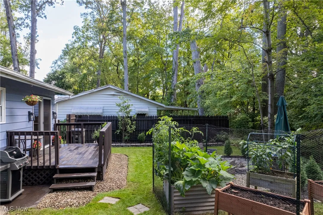 View of yard with a deck, a garden, and view of scattered trees