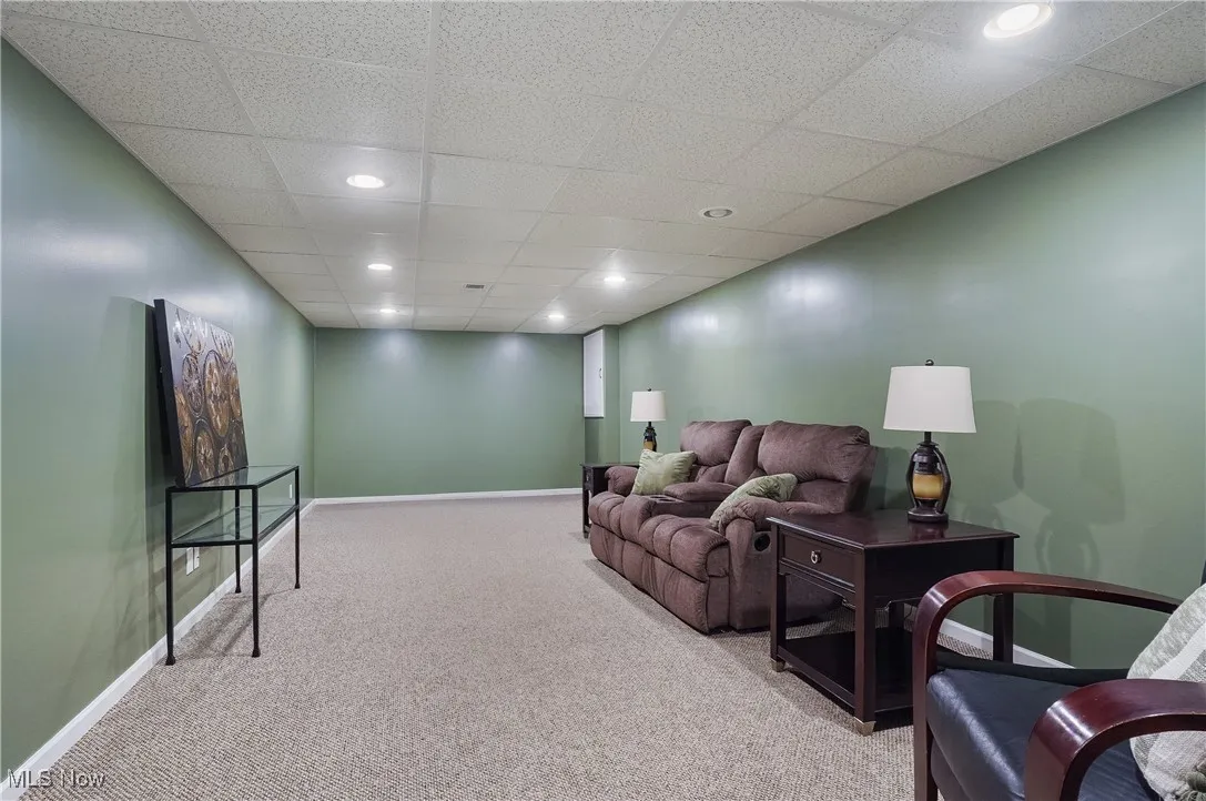 Living area with carpet flooring, recessed lighting, and a paneled ceiling
