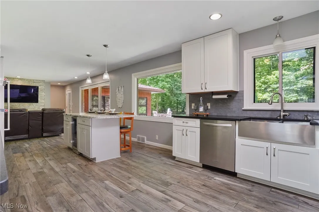 Kitchen featuring pendant lighting, white cabinetry, open floor plan, stainless steel dishwasher, and recessed lighting