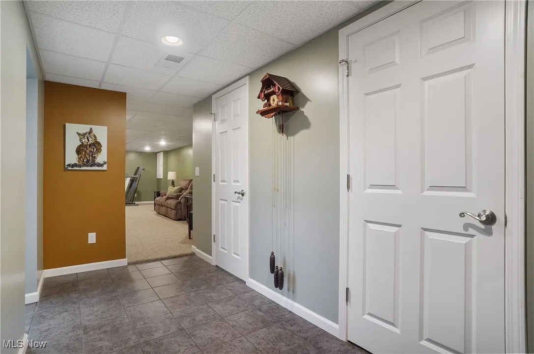 Hallway with a drop ceiling, dark tile patterned floors, dark colored carpet, and recessed lighting