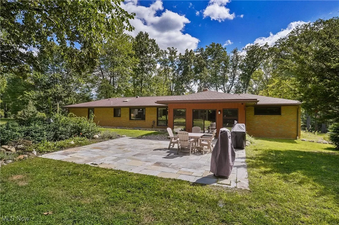 Back of house with a patio area, a yard, and brick siding