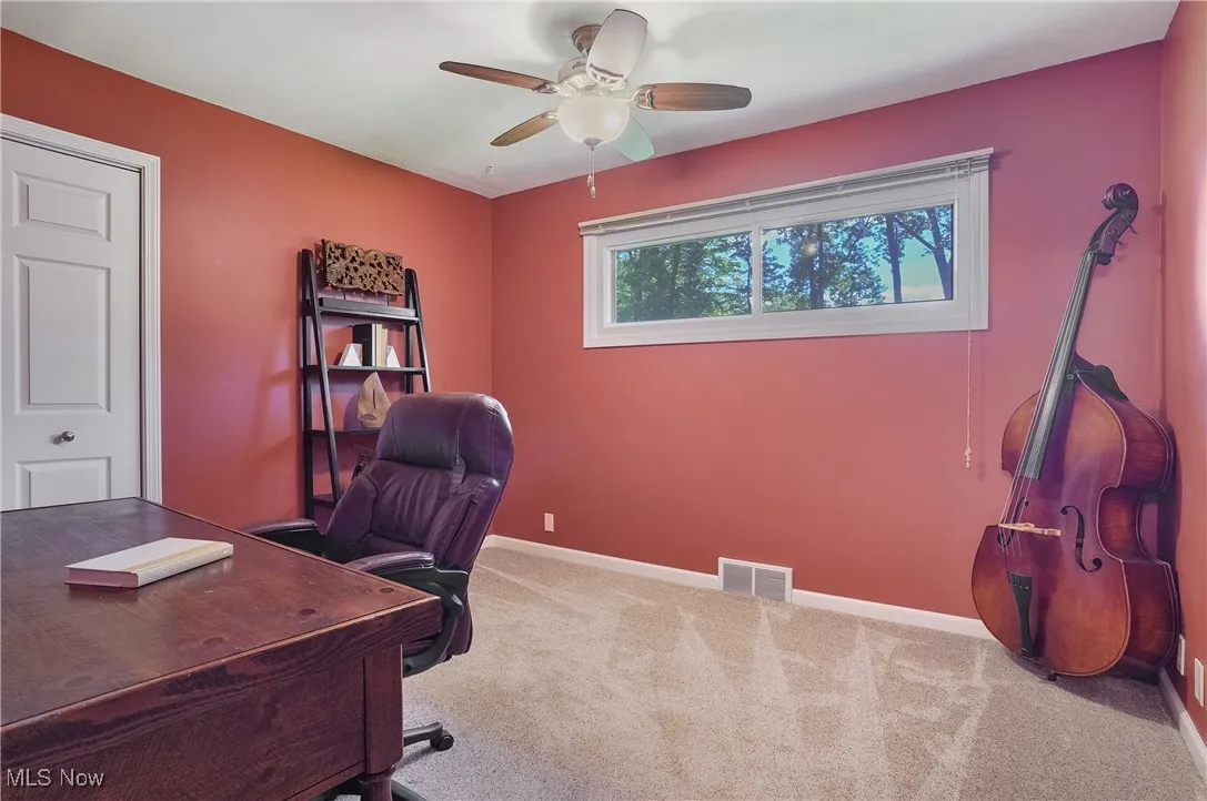 Carpeted home office featuring baseboards and ceiling fan