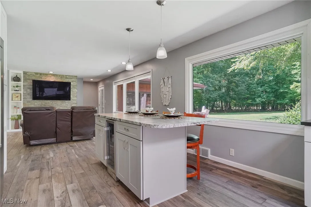 Kitchen with hanging light fixtures, a breakfast bar, light wood-type flooring, a center island, and recessed lighting