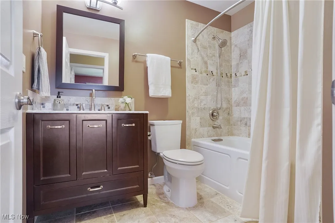 Bathroom with shower / tub combo with curtain, vanity, and light tile patterned floors