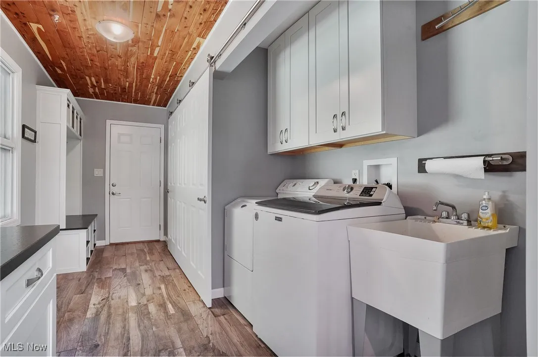 Laundry room featuring cabinet space, light wood-type flooring, wood ceiling, and washer and clothes dryer