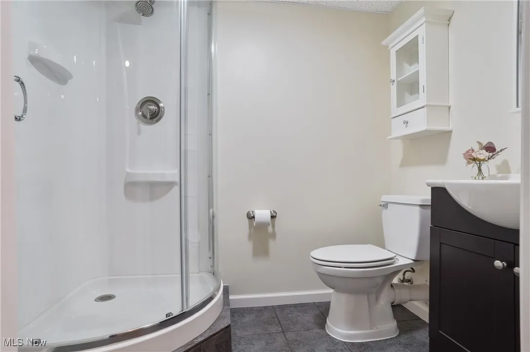 Bathroom with vanity, dark tile patterned floors, and a stall shower