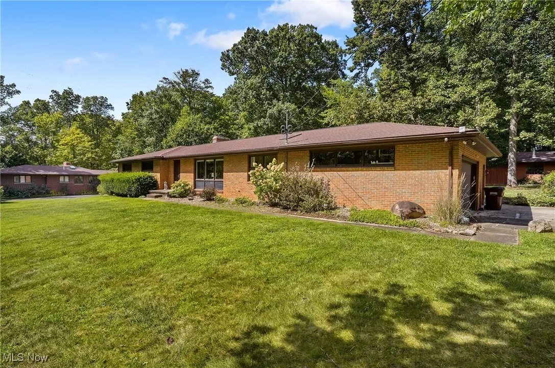 Ranch-style home featuring brick siding, a front yard, a chimney, and a garage