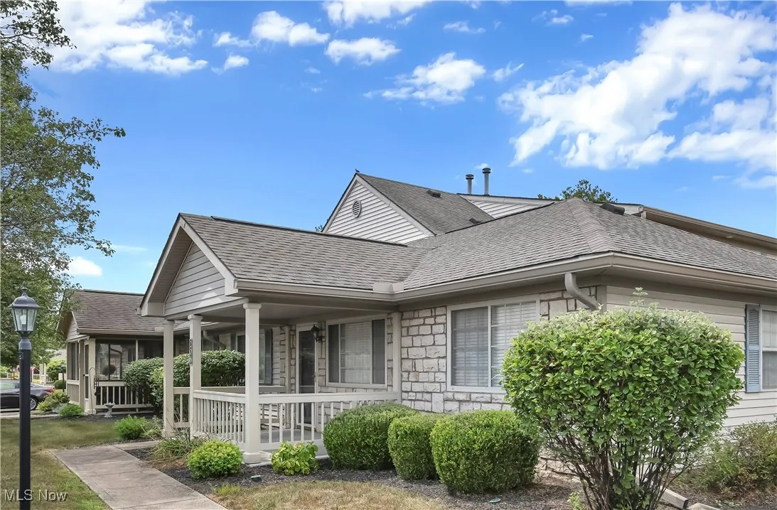 View of side of home with a shingled roof and covered porch