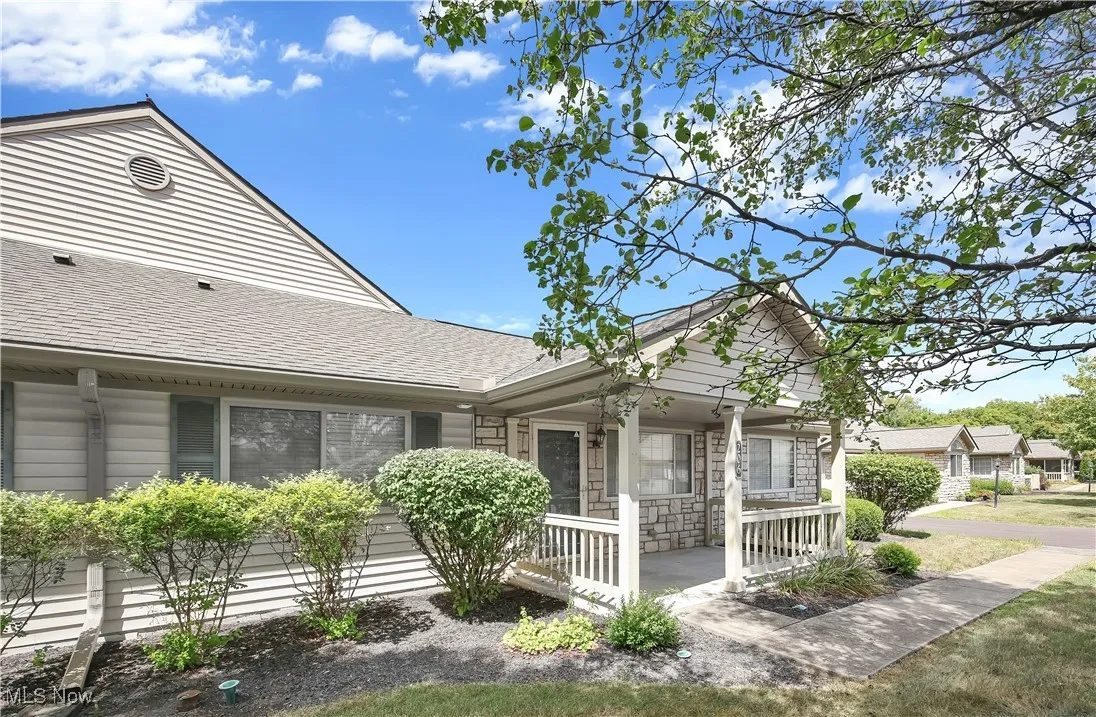 View of front of home featuring a porch, roof with shingles, and stone siding