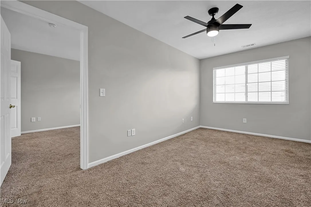 Carpeted empty room with baseboards and ceiling fan