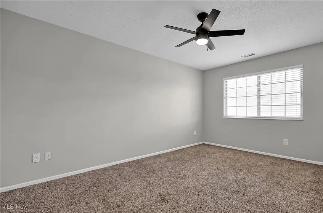 Carpeted spare room with a textured ceiling and a ceiling fan