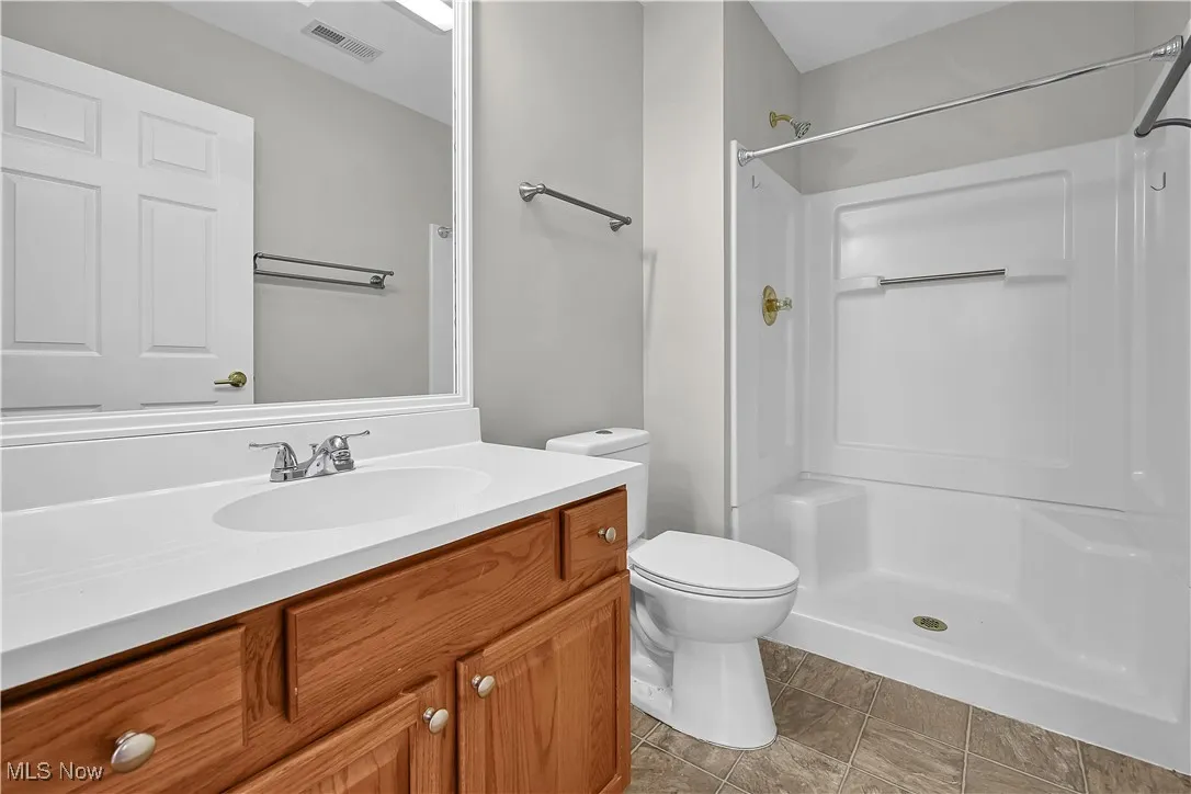 Full bathroom with vanity, a stall shower, and light tile patterned floors