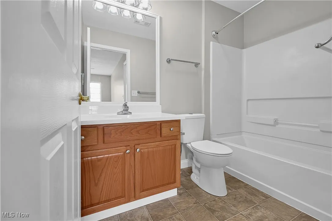 Full bath featuring  shower combination, vanity, and dark tile patterned flooring