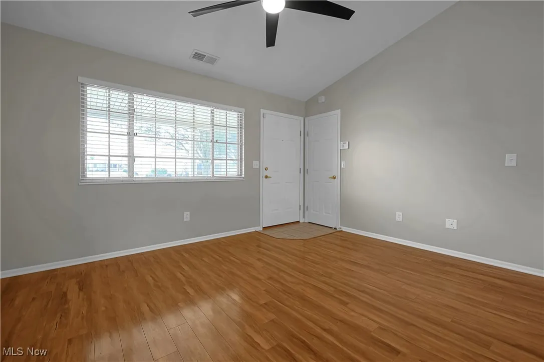 Empty room with lofted ceiling, light wood-style flooring, and a ceiling fan