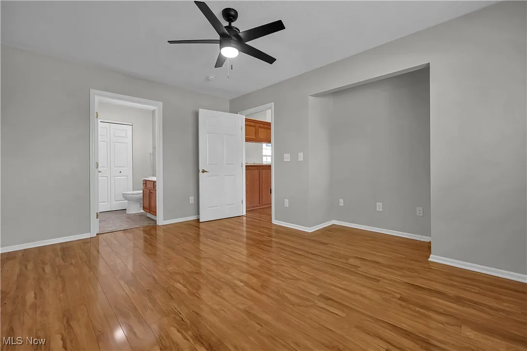 Unfurnished bedroom featuring light wood-style floors, ceiling fan, and connected bathroom