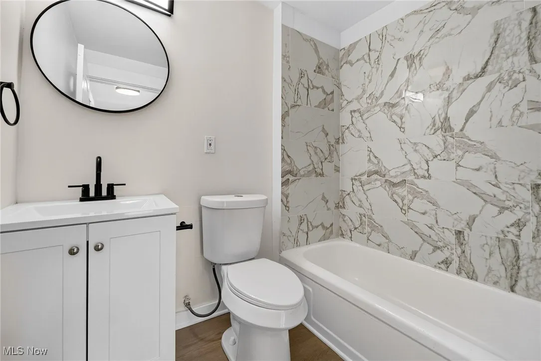 Bathroom featuring vanity, bathtub / shower combination, and wood finished floors
