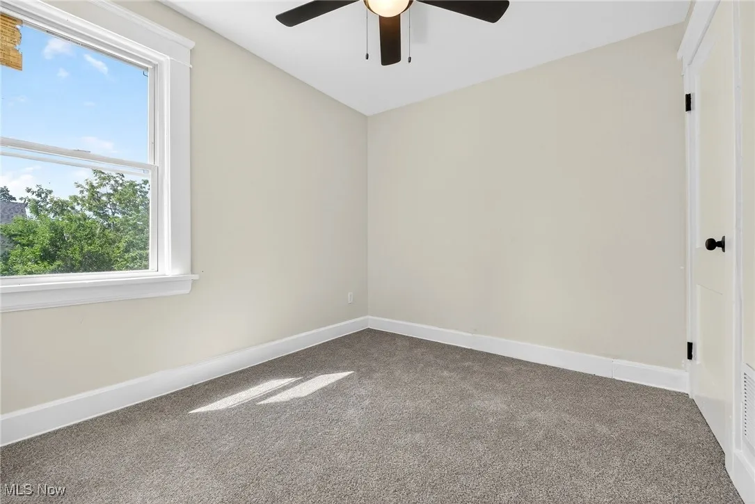 Carpeted empty room with baseboards and a ceiling fan