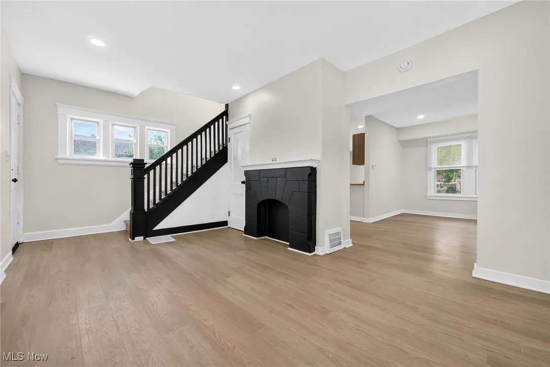 Unfurnished living room featuring light wood-type flooring, stairs, and recessed lighting