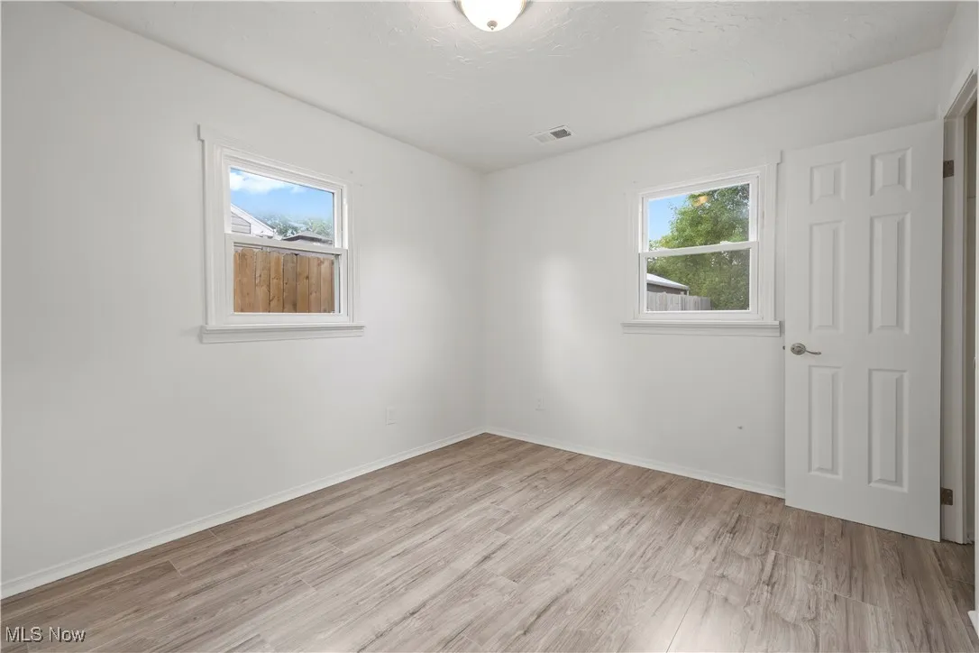 Unfurnished room with light wood-style floors, healthy amount of natural light, and a textured ceiling