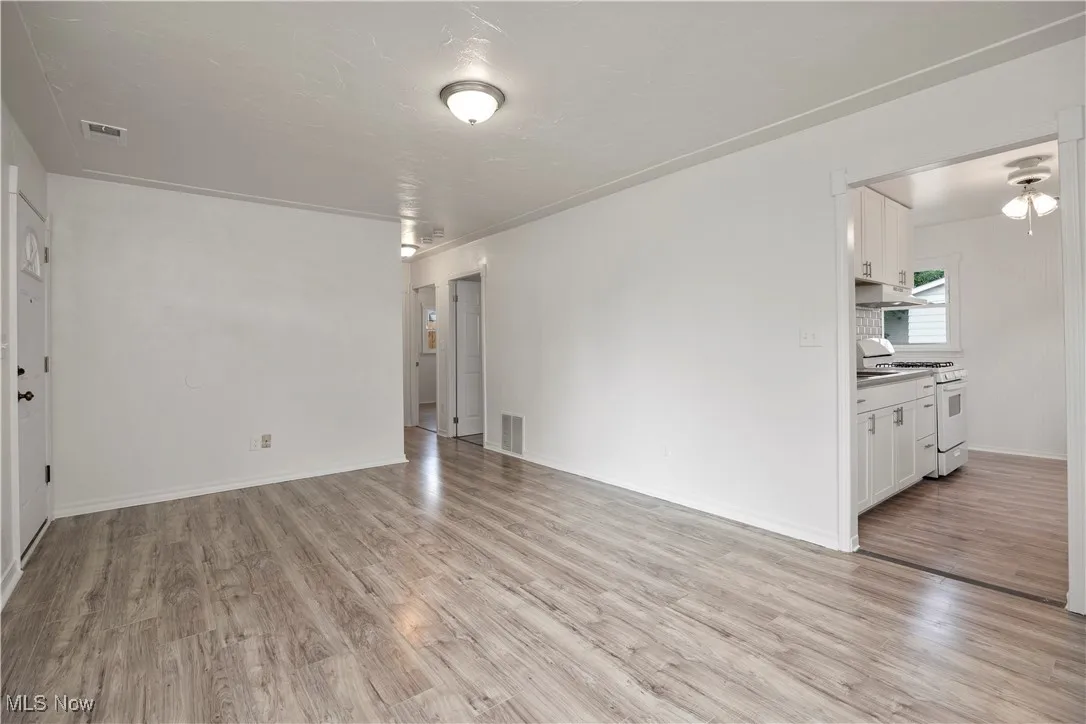 Unfurnished living room featuring light wood-type flooring and baseboards