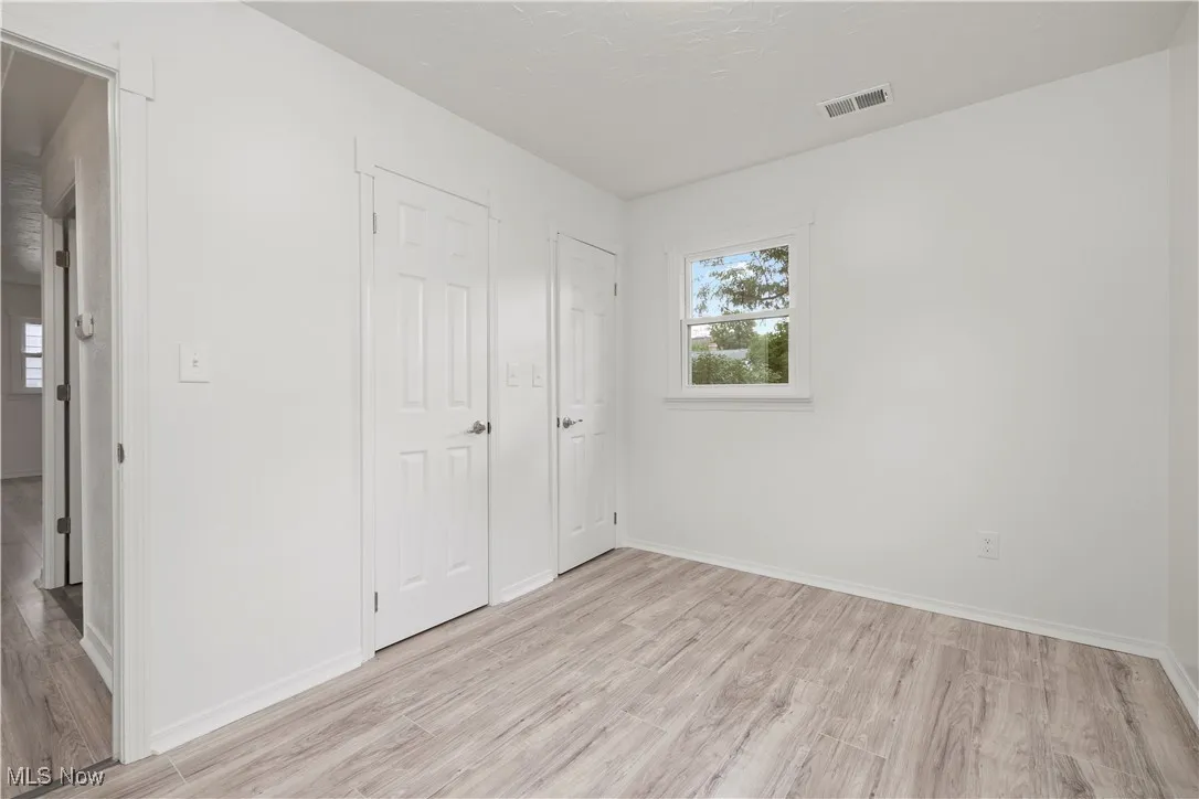 Unfurnished bedroom with light wood-style floors and baseboards