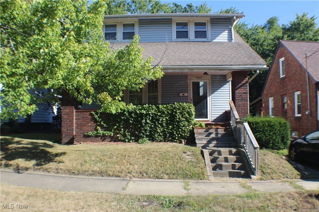 View of front of house with a front lawn, a porch, brick siding, and a shingled roof