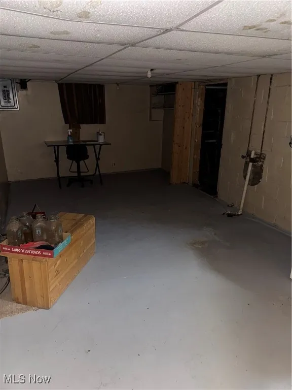 Finished below grade area with concrete block wall and a paneled ceiling