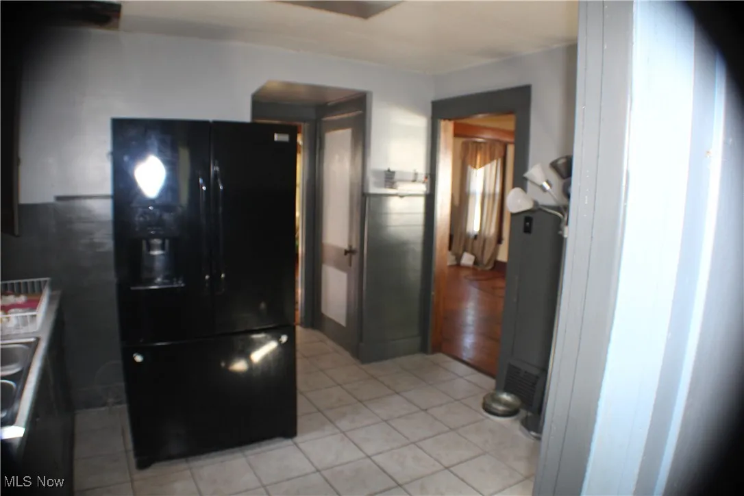 Kitchen with black fridge and light tile patterned floors