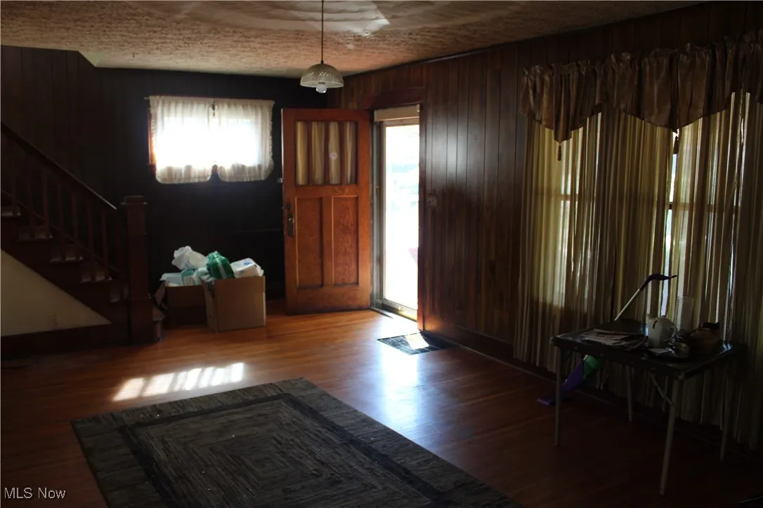 Foyer entrance with wood walls, wood finished floors, and stairs