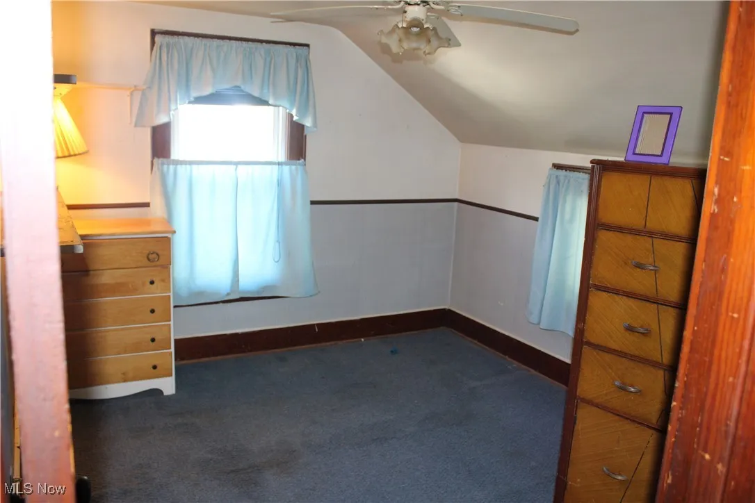 Bonus room with dark carpet, vaulted ceiling, and ceiling fan