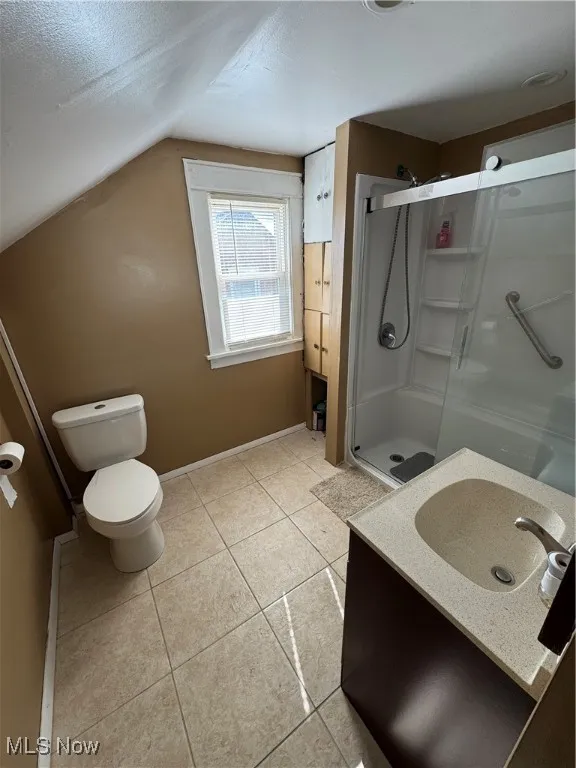 Bathroom with a shower stall, light tile patterned floors, vanity, a textured ceiling, and lofted ceiling