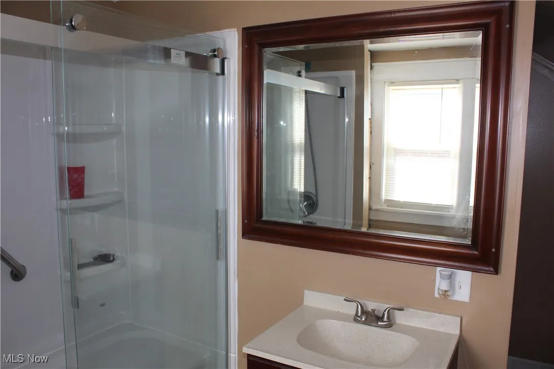 Full bath featuring a stall shower and vanity