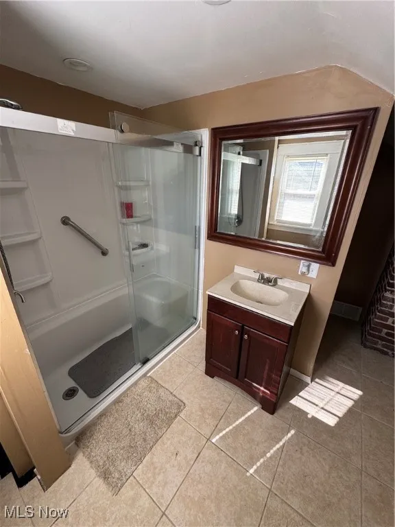 Full bathroom with a stall shower, vanity, and light tile patterned flooring