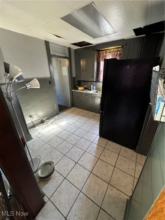 Kitchen with black refrigerator, light tile patterned floors, and light countertops