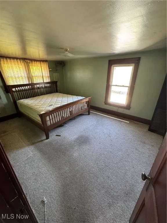 Carpeted bedroom featuring baseboards and a textured ceiling