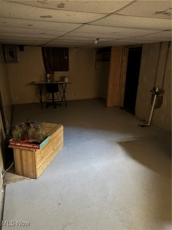 Finished basement with a paneled ceiling and electric panel