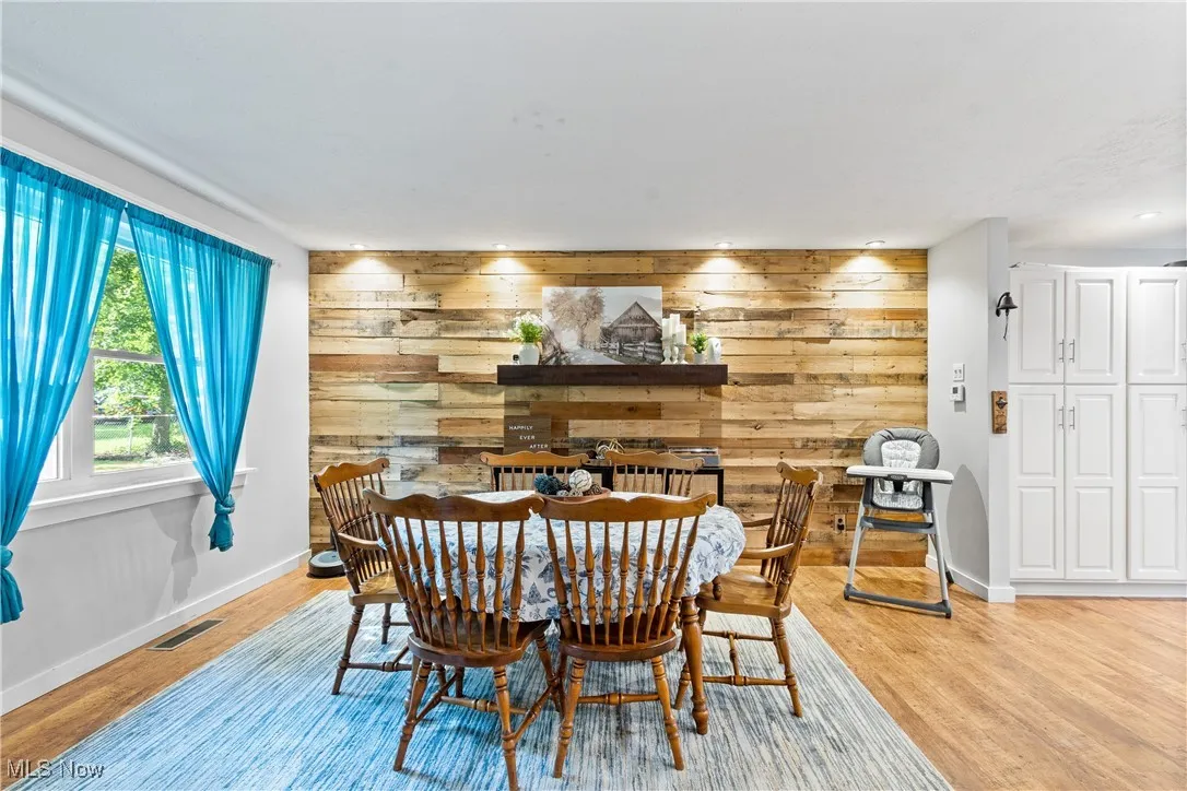 Dining space with wooden walls and light wood-style flooring