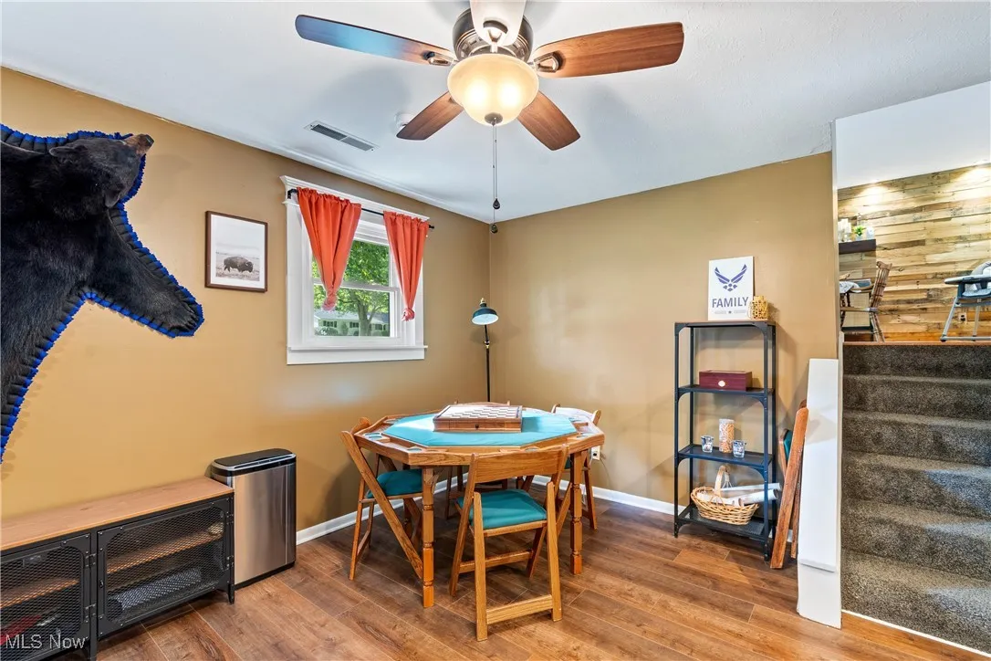 Dining room with stairs, wood finished floors, and ceiling fan
