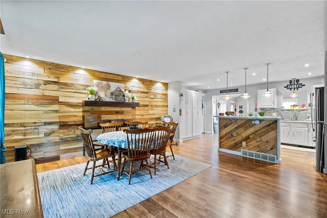 Dining room featuring light wood-style flooring, recessed lighting, and wood walls