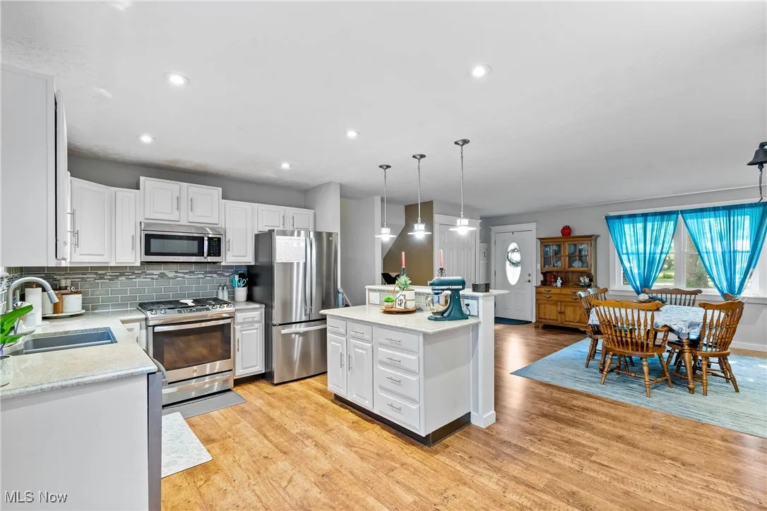 Kitchen featuring white cabinetry, appliances with stainless steel finishes, decorative backsplash, light wood-type flooring, and recessed lighting