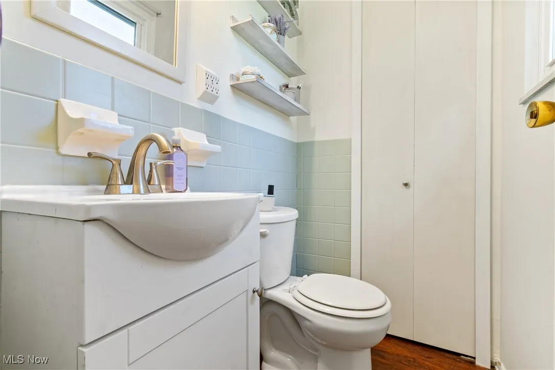 Bathroom featuring vanity, tile walls, and dark wood-style floors