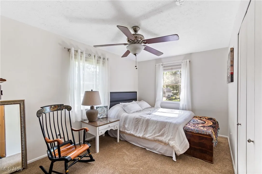 Carpeted bedroom featuring a textured ceiling and ceiling fan