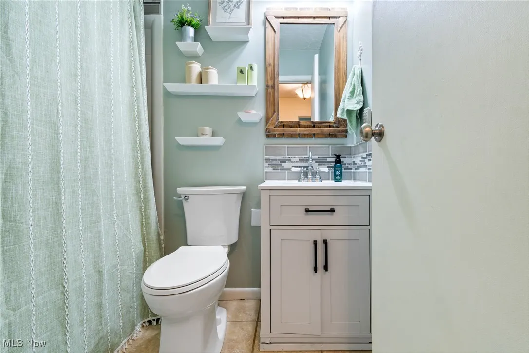 Bathroom featuring decorative backsplash, vanity, light tile patterned floors, and a shower with shower curtain