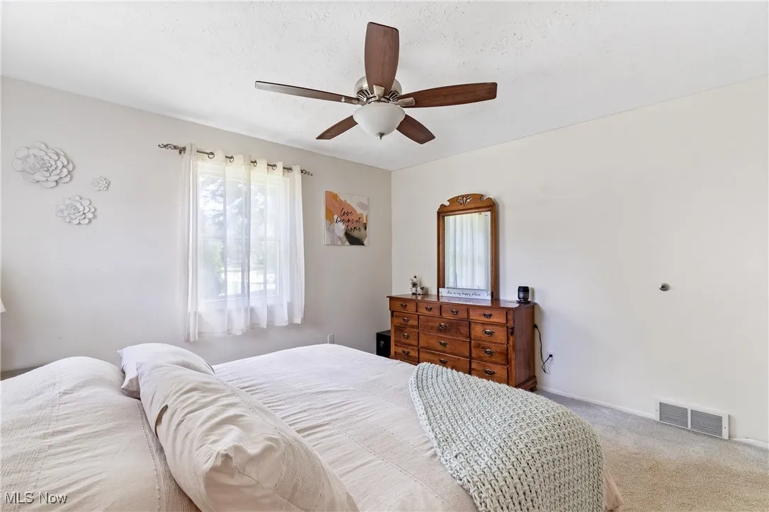 Carpeted bedroom featuring a textured ceiling and ceiling fan