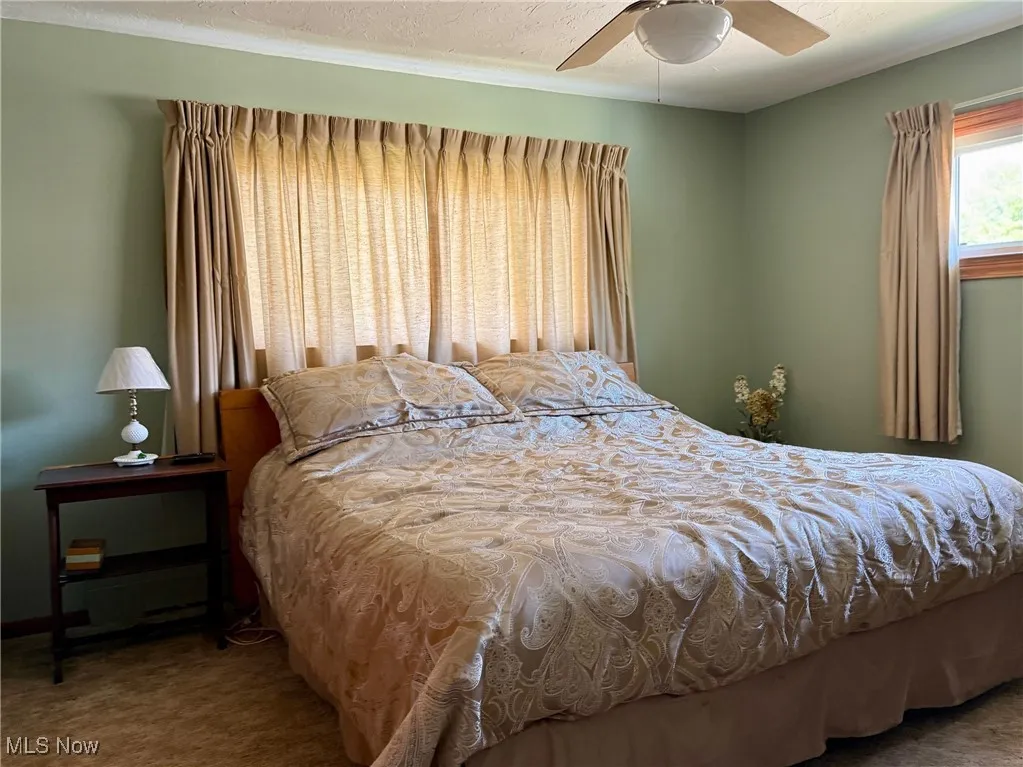 Carpeted bedroom with a textured ceiling and a ceiling fan