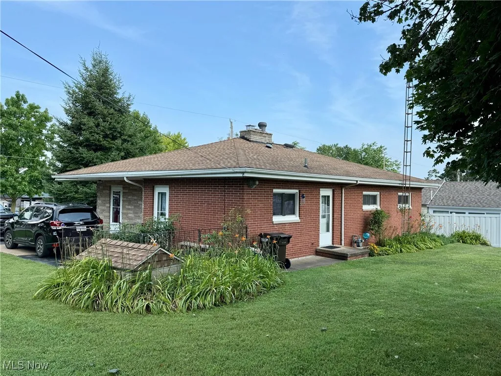 Back of house with brick siding, a chimney, and a shingled roof